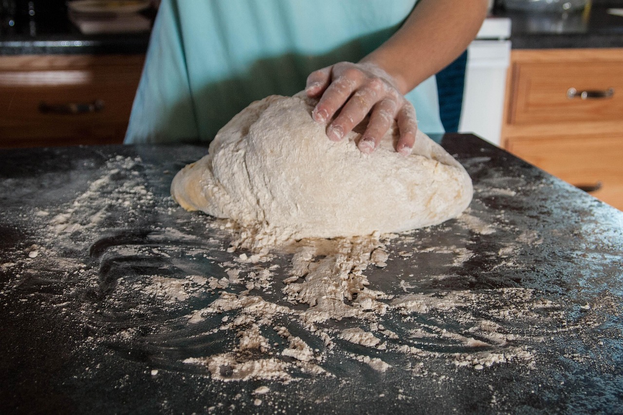 Bread dough being kneaded with flour during recipe preparation
