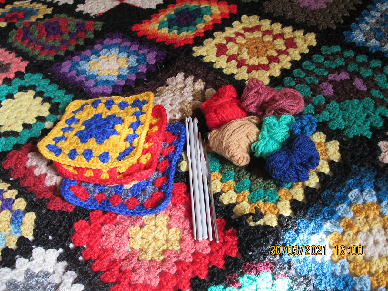 Crocheted blanket with yarn and tools nearby