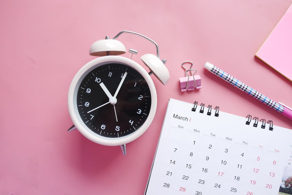 Desk with an alarm clock and planner representing time allocation and scheduling